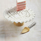 happy cake pedestal set on a whitewashed wooden surface with a slice of cake