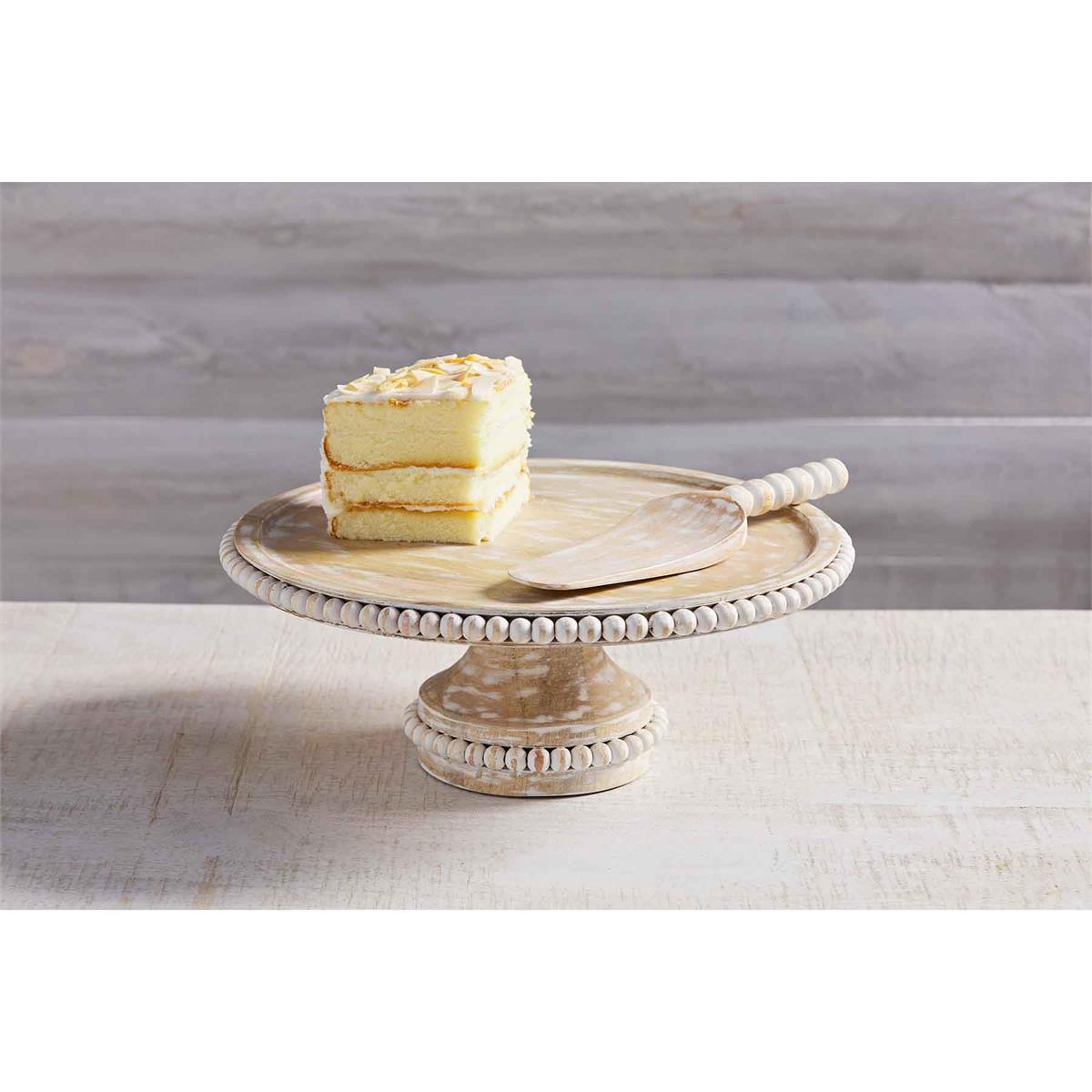 wooden beaded cake stand displayed with a slice of cake on a white wooden surface
