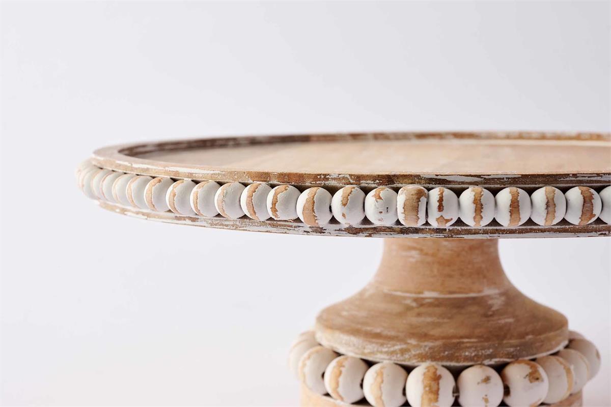 close up view of the wooden beaded cake stand against a white background