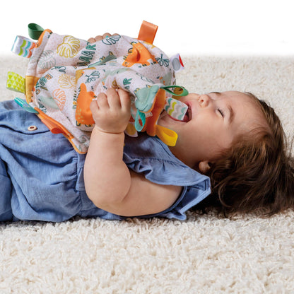 a little girl playing with the dinosaur lovey while laying on a white rug