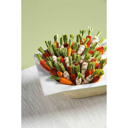 all three colors and patterns of mini carrots displayed in a white dough bowl on a white linen tablecloth against a pale green background