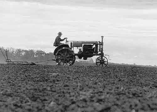front of card is a photograph of a man driving an old tractor in a field