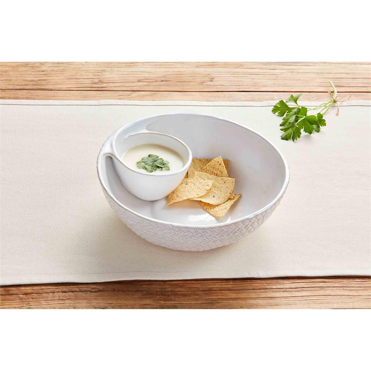 textured chip and dip filled with a few chips and dip while displayed on a white table runner on a wood slat table