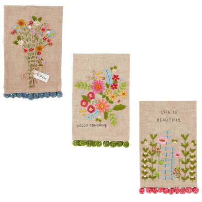 all three styles of floral embroidered pom towel displayed against a white background
