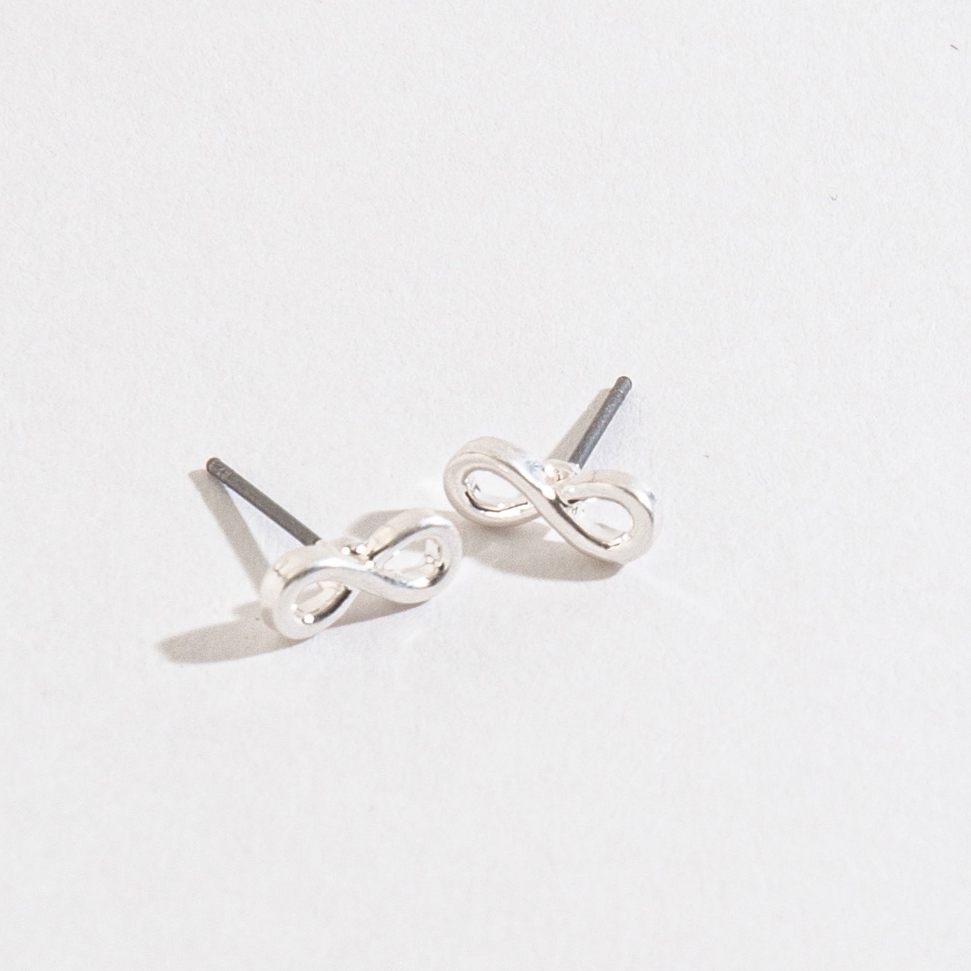 silver infinity stud earrings on a white background