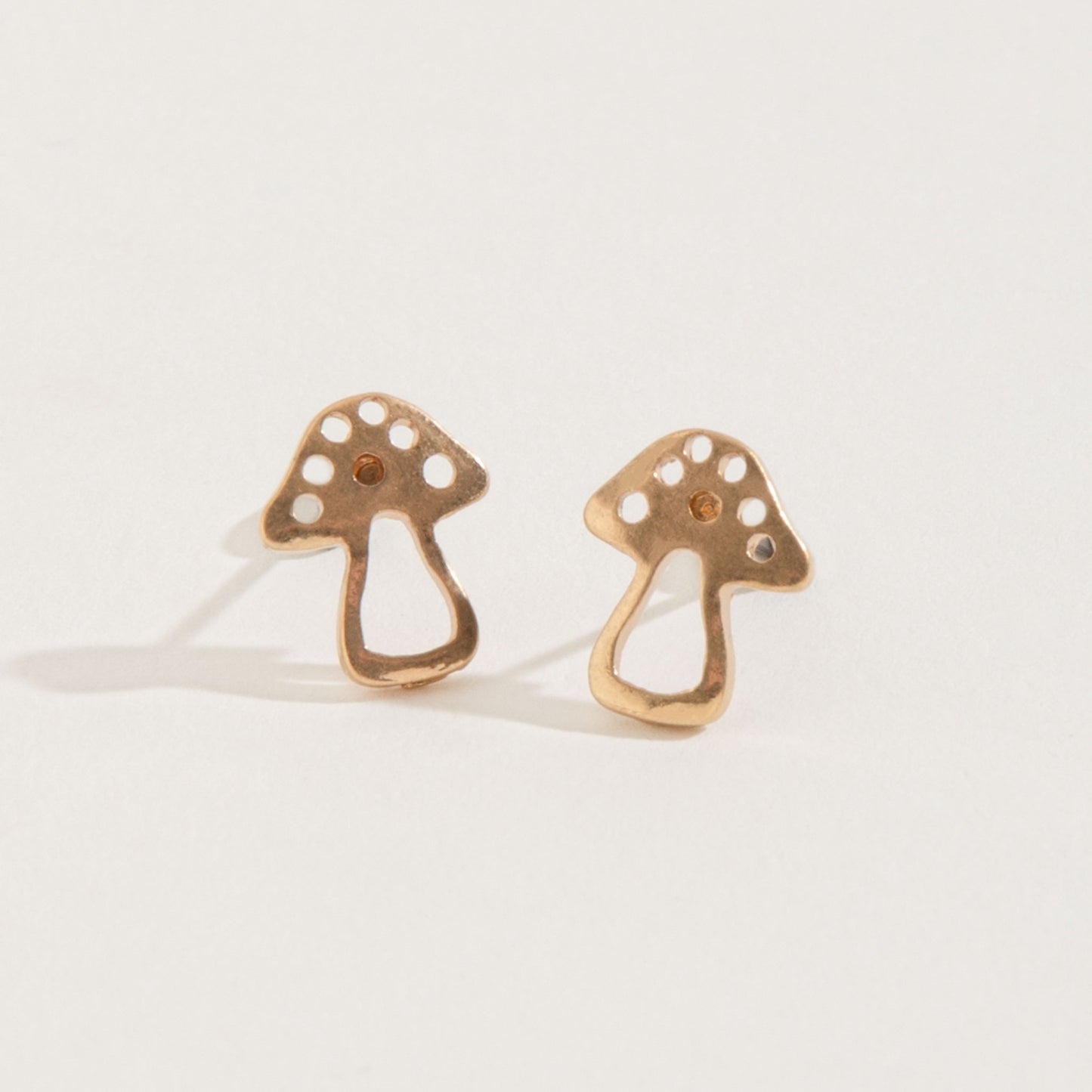 gold mushroom stud earrings on a white background