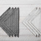 two styles of folded napkins on a gray wood slat surface