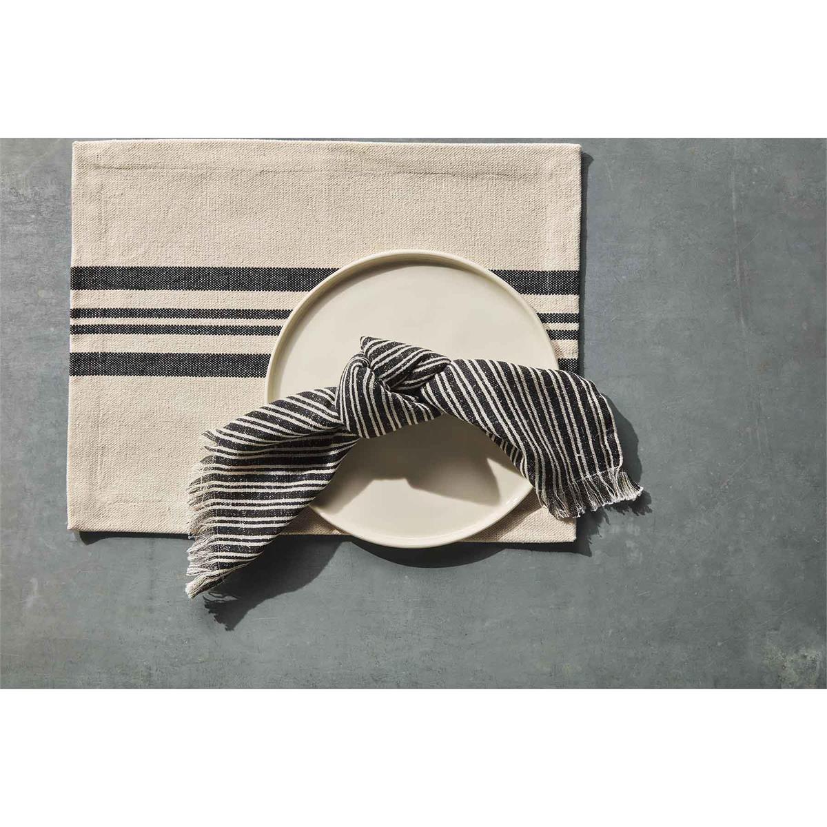stripe napkin displayed with a dinner plate on top of a placemat sitting on a gray surface