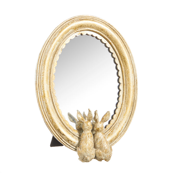 oval mirror is gold with two small rabbits peering into the mirror displayed against a white background