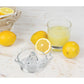 the glass juicer displayed on a mostly white countertop surrounded by lemons and a glass of lemonade