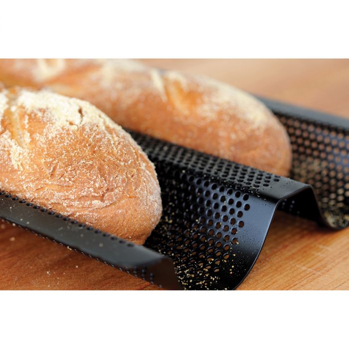 two loaves of baguettes displayed in the double baguette baking pan on a wooden surface