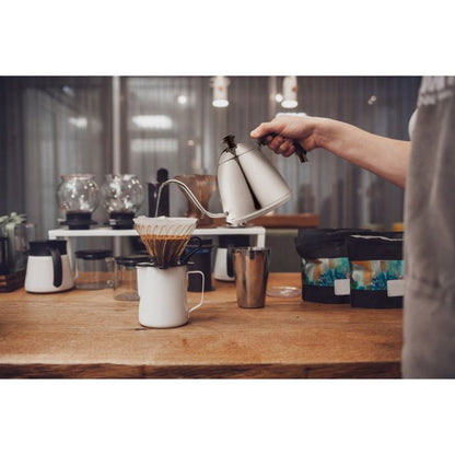 illustration of a person using the pour over gooseneck kettle in a kitchen preparing a cup of coffee