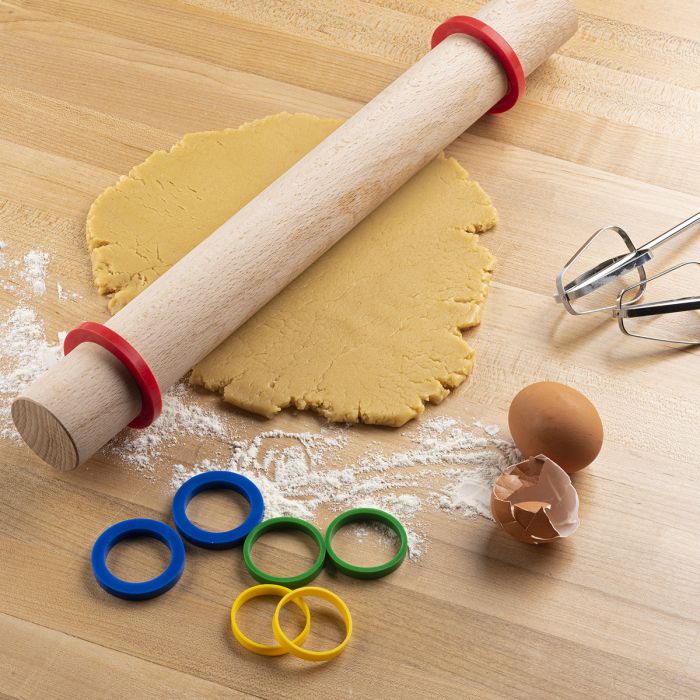 the silicone rolling pin rings displayed on a rolling pin with rolled dough beside egg shells on a light wood surface