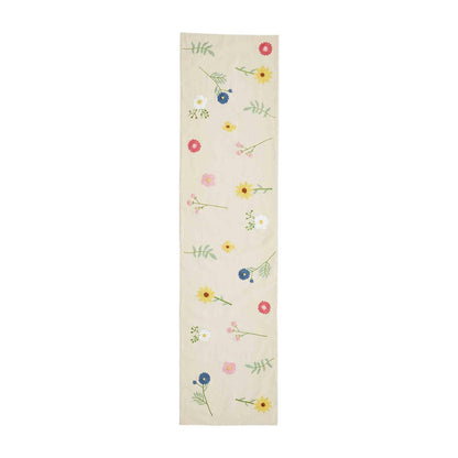 bloom table runner is tan with multiple small spring flowers embroidered all around against a white background