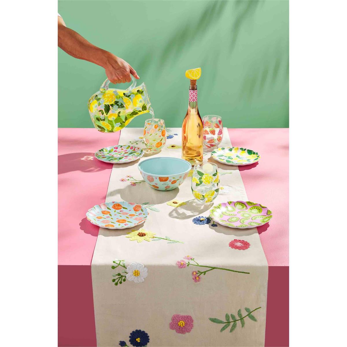 bloom table runner displayed on on a table with plates, bowl, and glasses being filled by a person