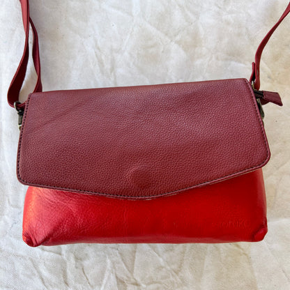 rounded red purse with maroon flap and red strap.