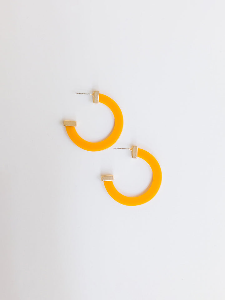 orange hoop earrings with gold ends on a white background.