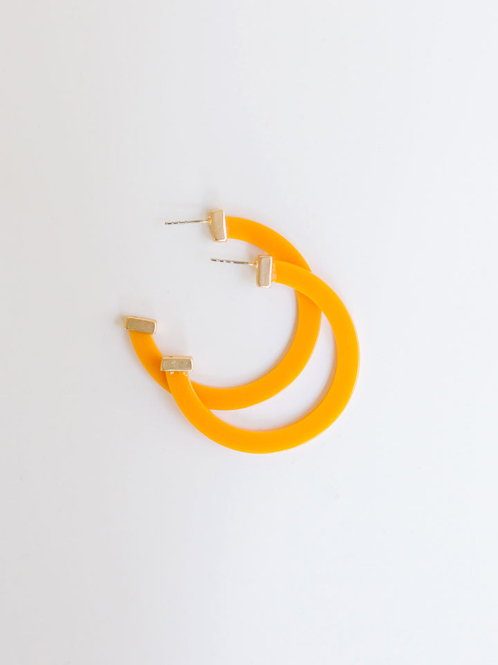 orange hoop earrings with gold ends on a white background.