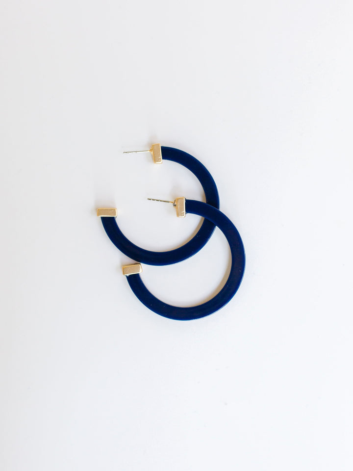 navy hoop earrings with gold ends on a white background.