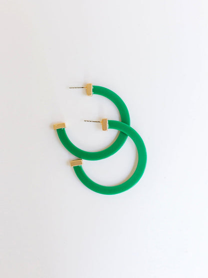 green hoop earrings with gold ends on a white background.