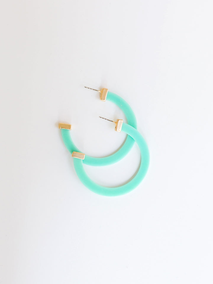 teal hoop earrings with gold ends on a white background.