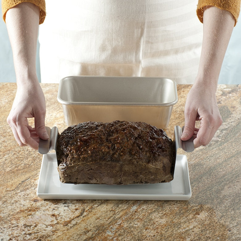 hands lifting insert filled with meat loaf out of pan.