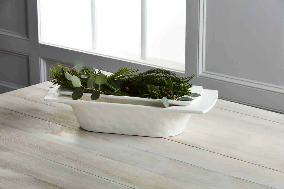 small and large dough bowls stacked together on a table and filled with greenery.
