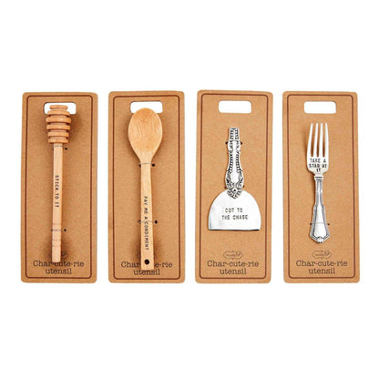 honey wand, wood spoon, cheese slicer, small fork displayed on card stock on a white background