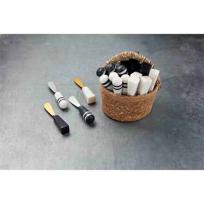 marble handled spreaders displayed in a woven basket with four laying beside it on a gray surface