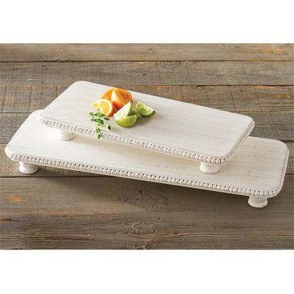 small and large beaded wood serving board with sliced oranges and limes on a rustic wood slat table against a white background