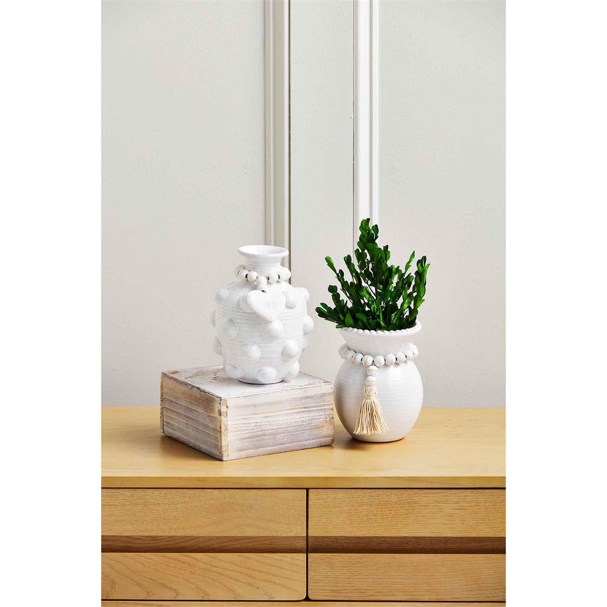both styles of raised dot pendant vases displayed on a hall table with a wooden box