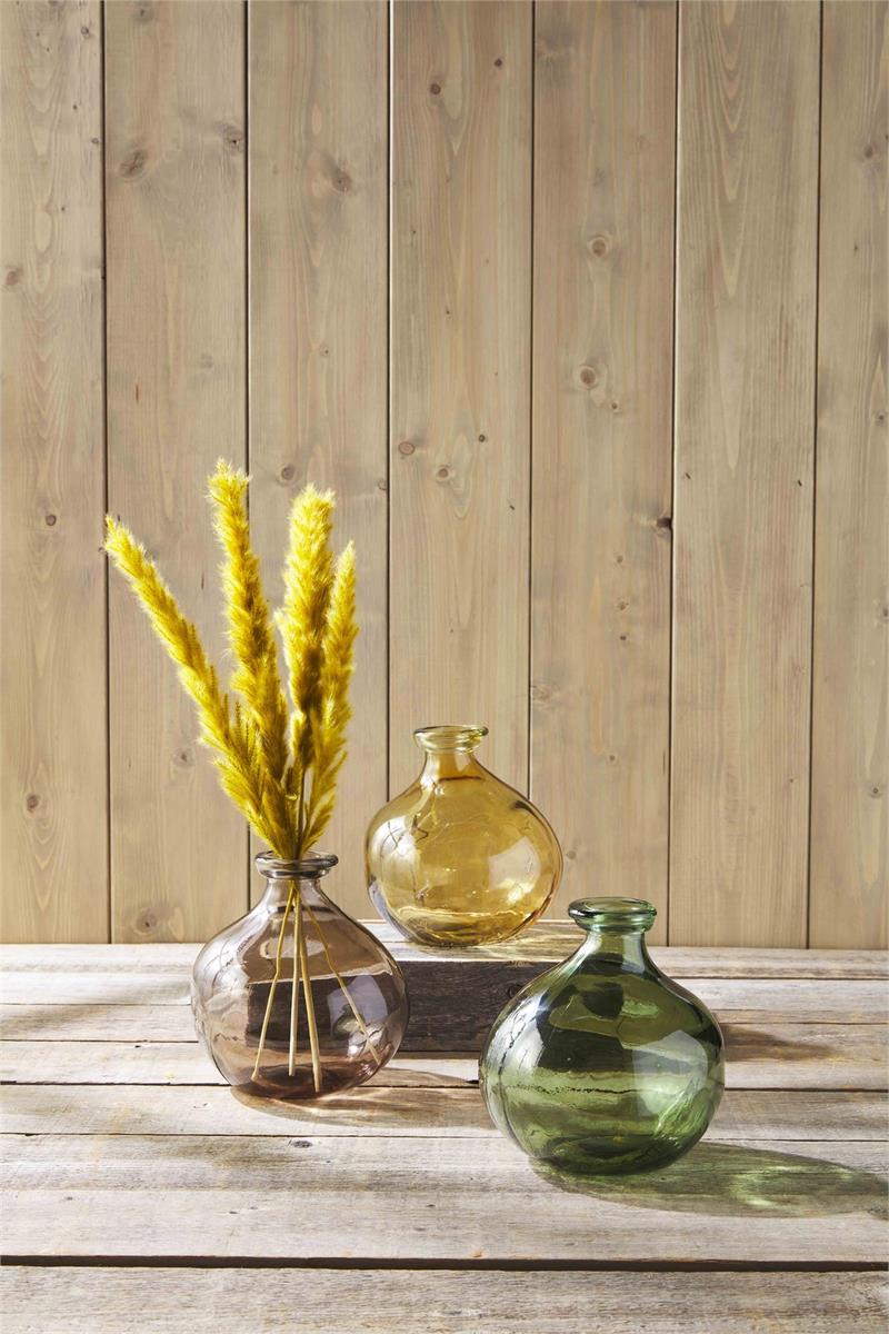 all three colors of spanish glass vases displayed on a rustic wood table in front of a rustic wood wall with one having gold flowers 
