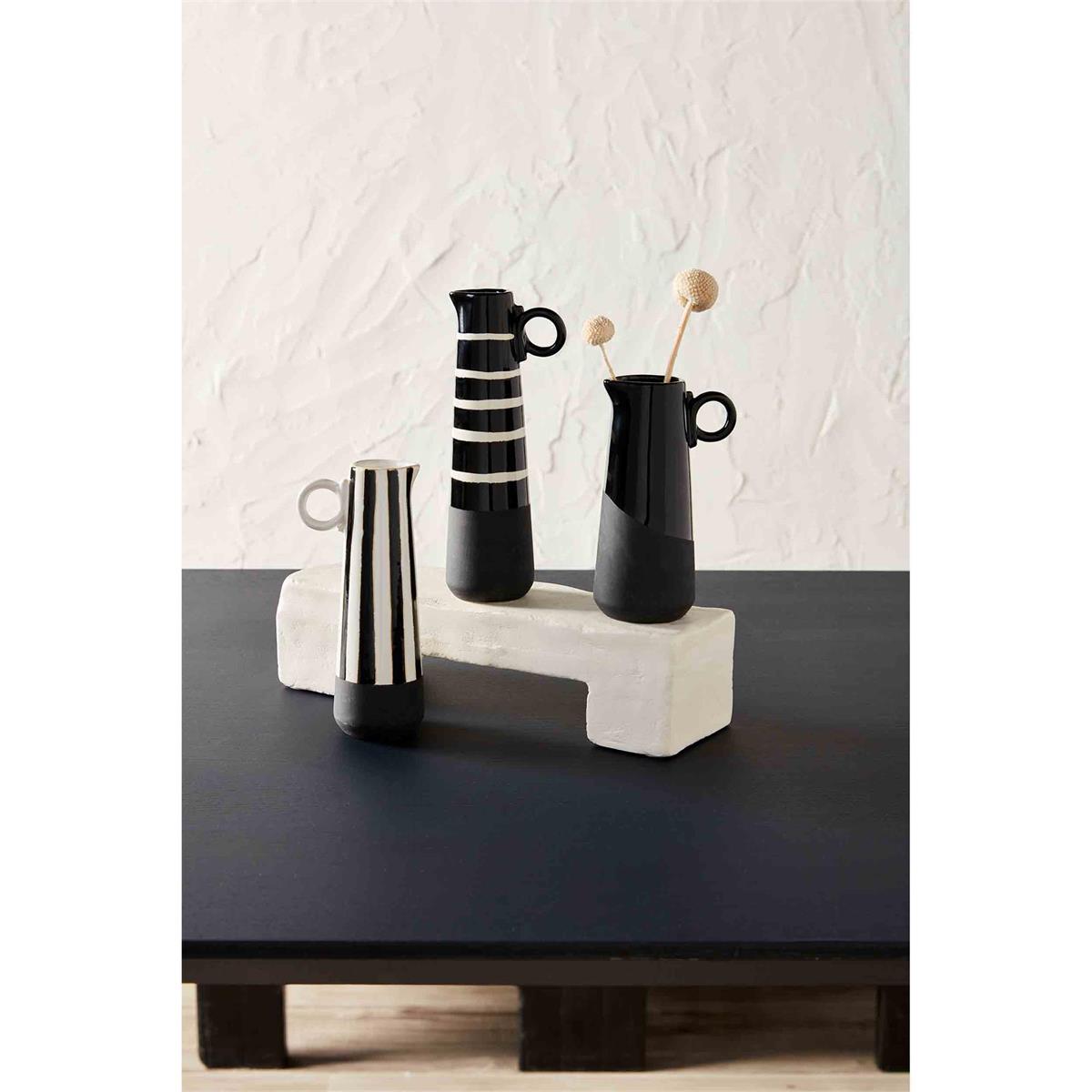 all three styles of black and white vases displayed on a black table with a white wood block against a white background