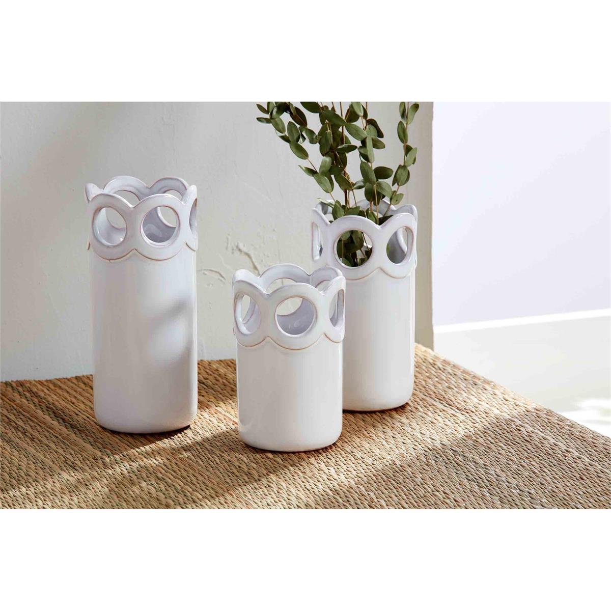 all three sizes of the scalloped bud vases displayed on a tan runner with one having dried greenery