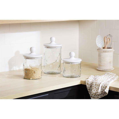 all three sizes of hobnail canisters displayed on a light wooden countertop in a kitchen next to a utensil holder and towel