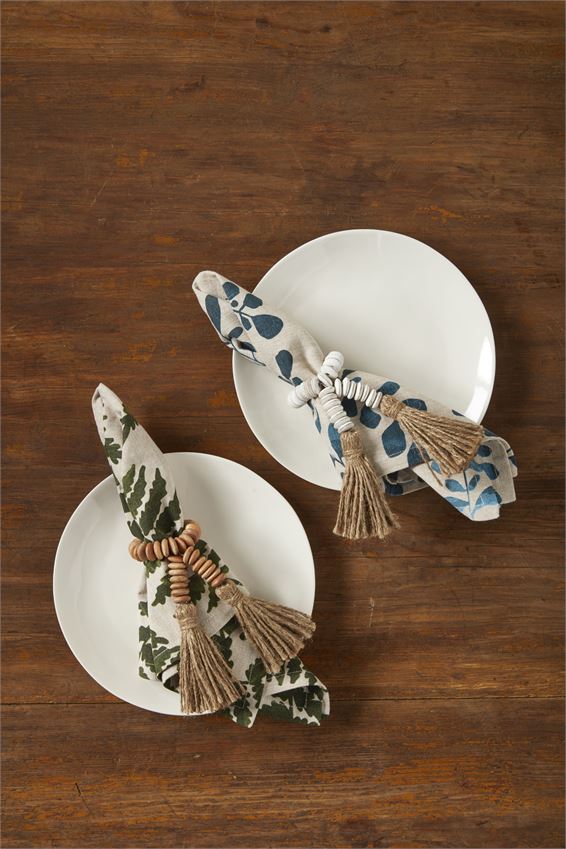 natural and white beaded napkin rings displayed with napkins and white plates on a dark wood table