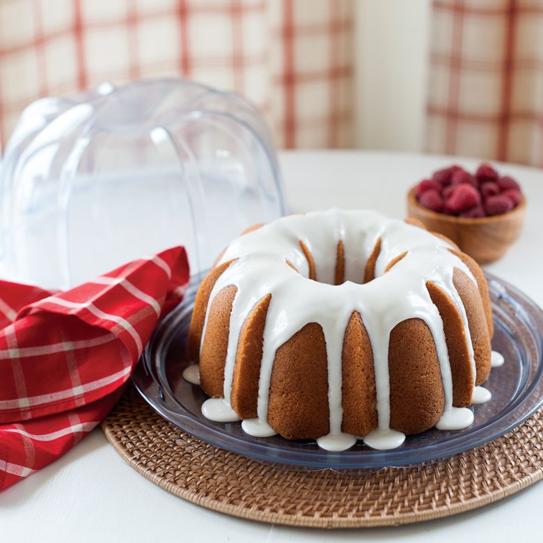 bundt cake on tray with cover in background.