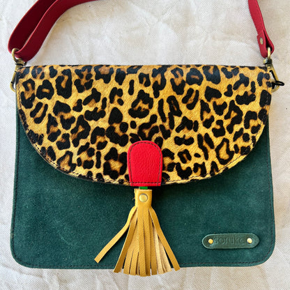 square dark green bag with brown and black cheetah print flap, yellow tassel, and red strap.