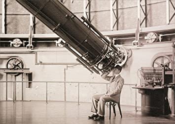 front of card is a photograph of an astronomer looking in a gigantic telescope