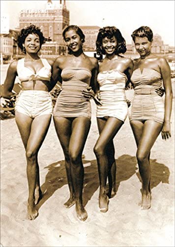 1960's photograph of four women in bathing suits with buildings in the background