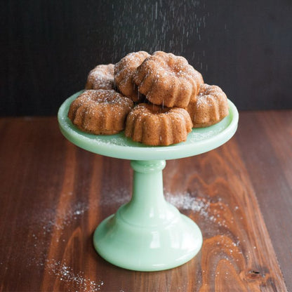 pedestal filled with mini bundt cake with powdered sugar.