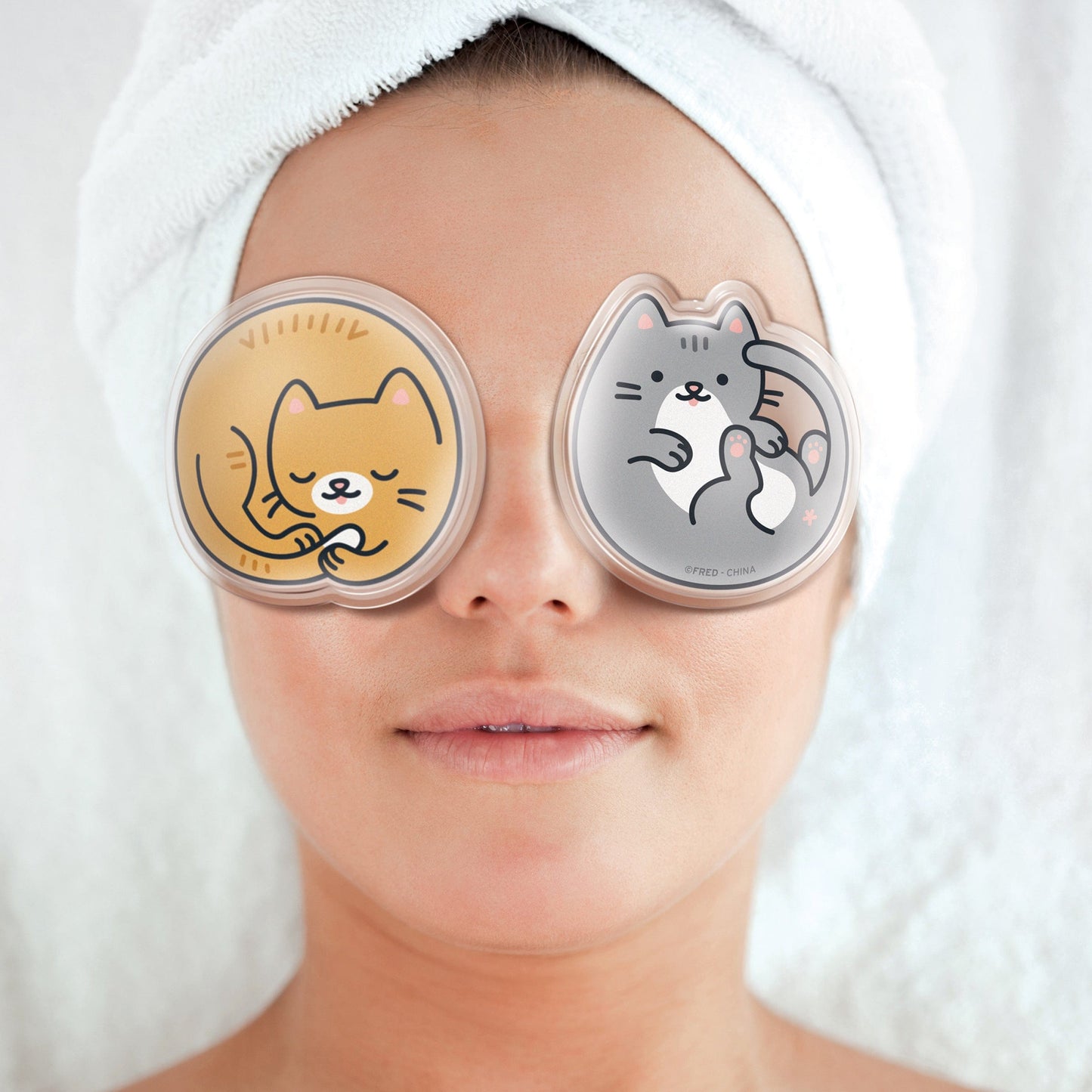 eye pads in the shape cats laying on a face with hair wrapped in towel