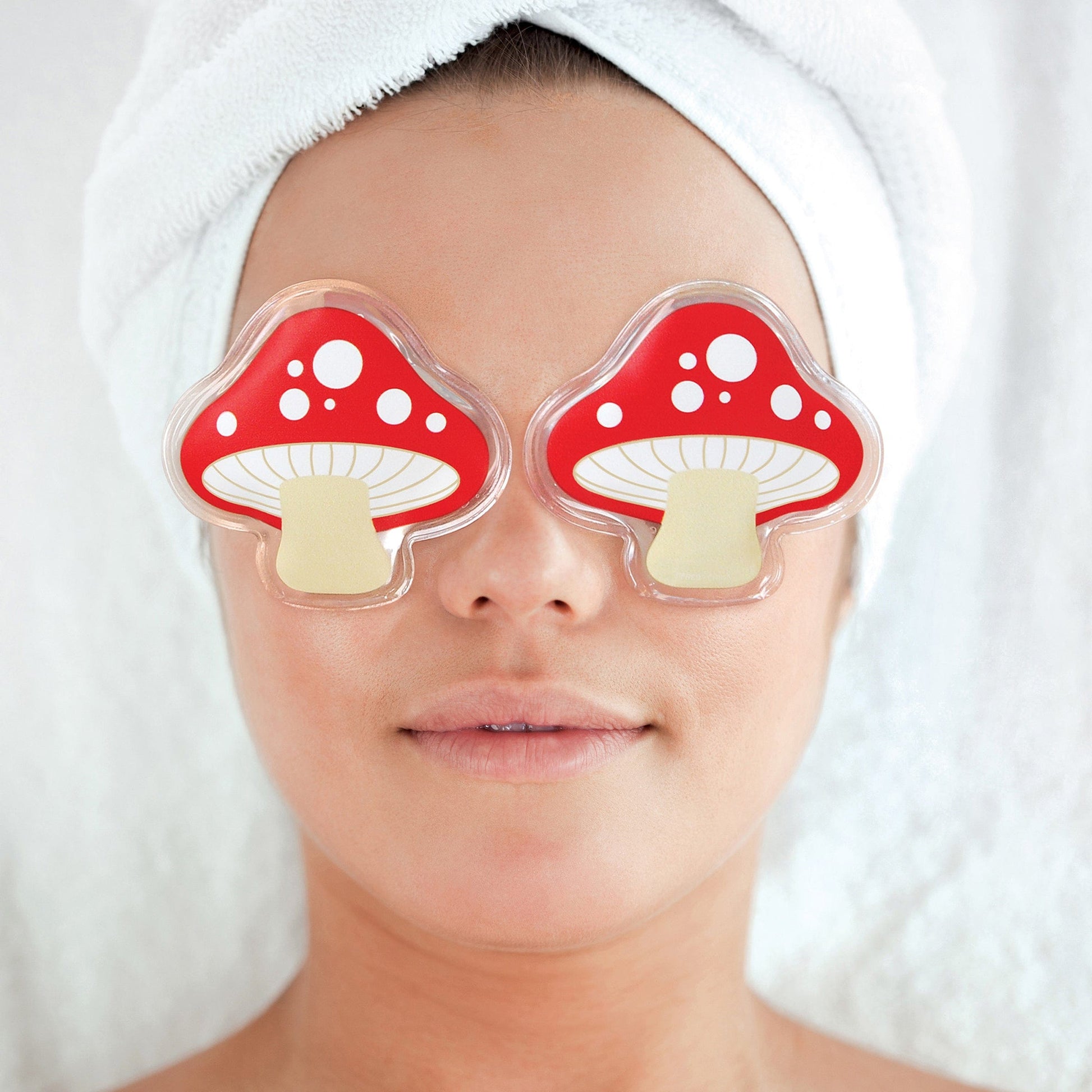 eye pads in the shape of mushrooms with red tops and white dots laying on a face with hair wrapped in towel