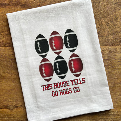 white towel with 2 rows of red and black footballs and text " this house yells go hogs go" underneath.