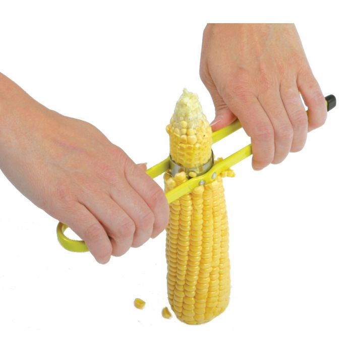 hands using corn cutter to cut corn off the cob.