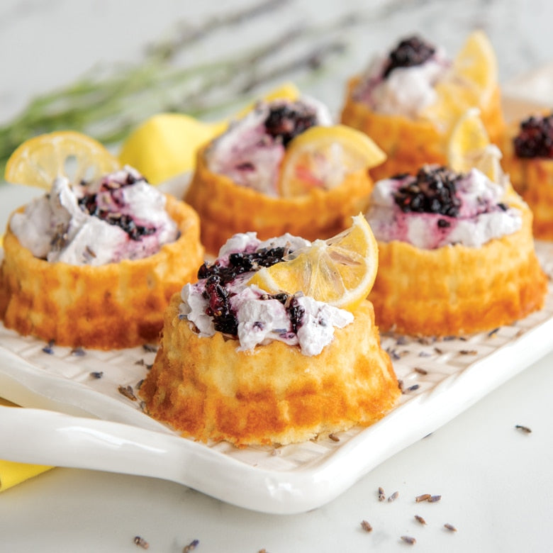 mini shortcake basket cakes topped with cream, blackberries, and lemon wedge.