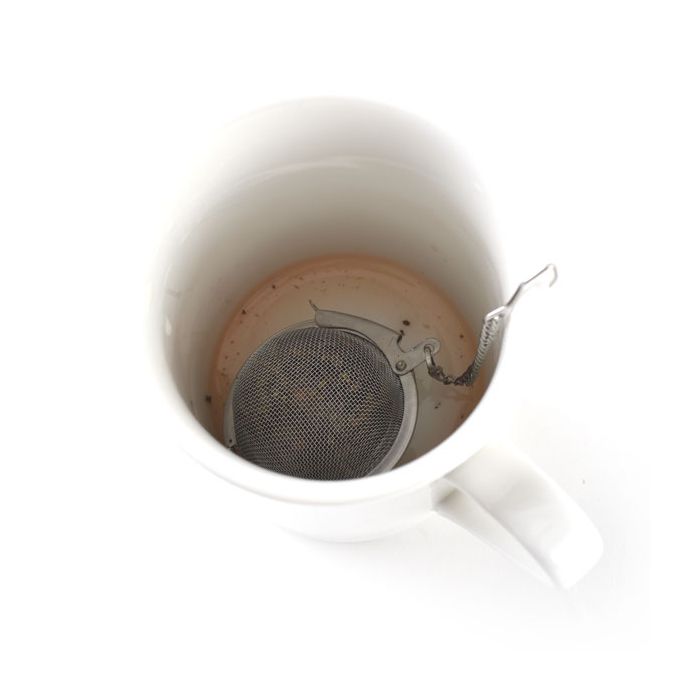 tea infuser filled with tea in mug.