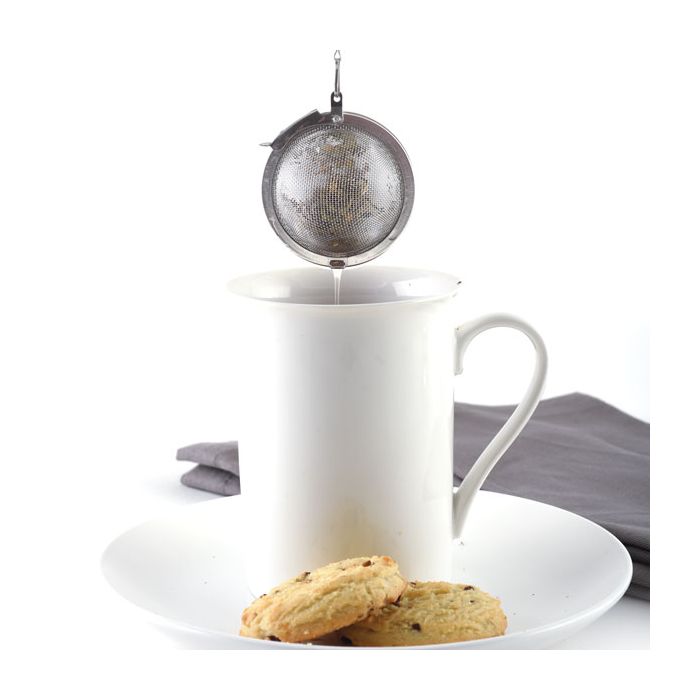 tea infuser filled with tea above mug.