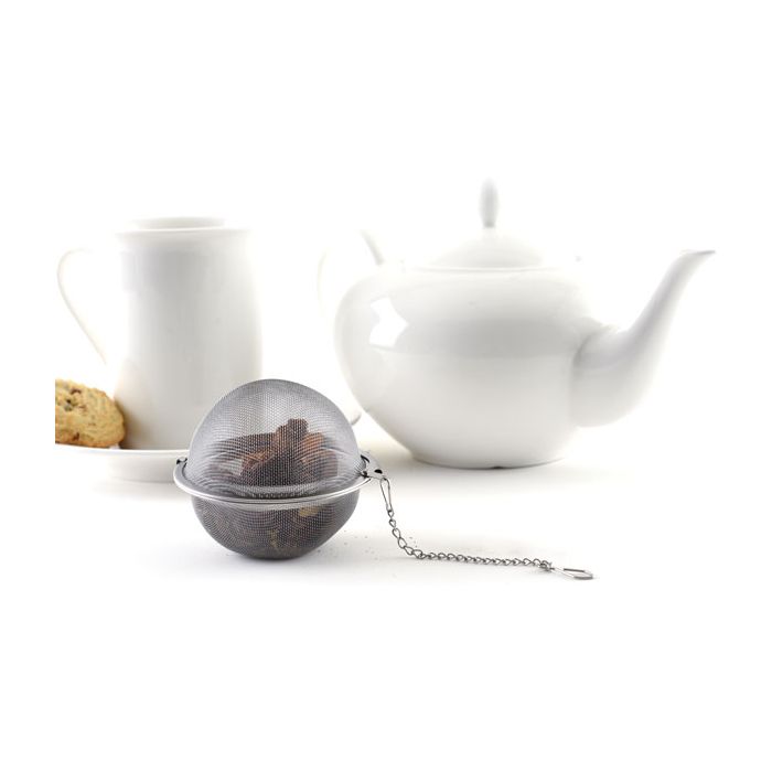 mesh tea infuser filled with tea next to teapot and mug.