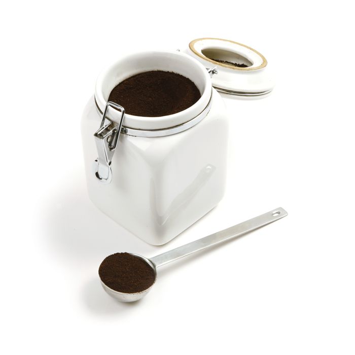 scoop filled with ground coffee next to canister of coffee.